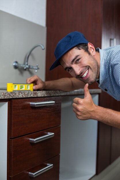 Uomo sorridente che mostra i pollici su mentre usando il livello di spirito