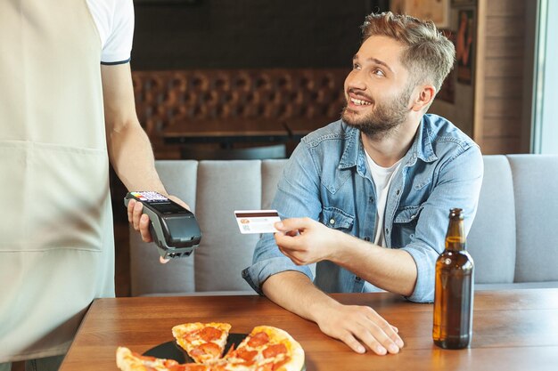 Uomo sorridente che paga con carta di credito nella caffetteria