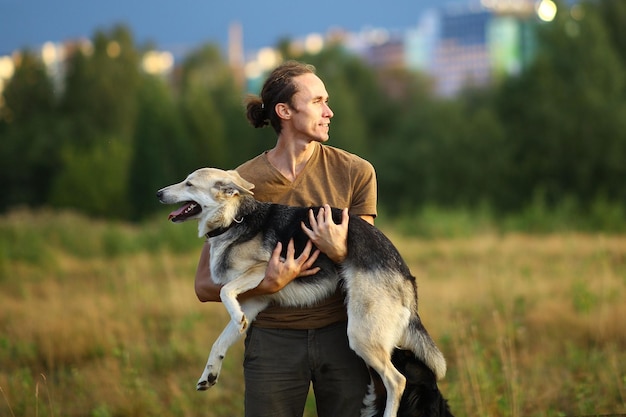Uomo sorridente che porta un cane mentre è in piedi su un terreno erboso