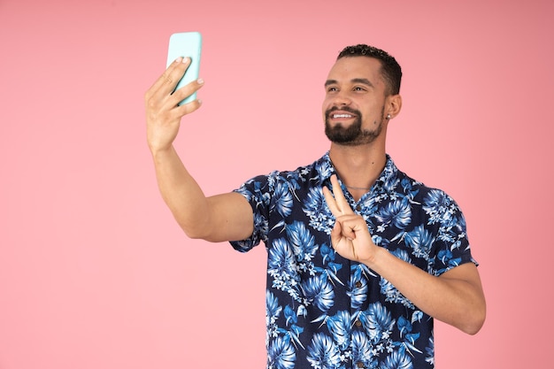 Uomo sorridente che prende un selfie facendo un segno di pace con la mano