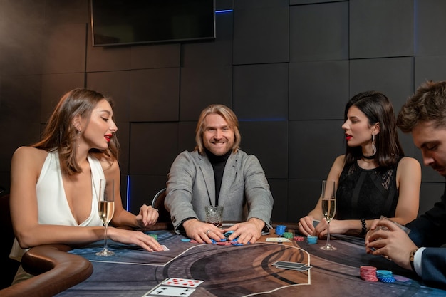 Uomo sorridente che rastrella un mucchio di fiches dopo il successo del gioco del poker nel casinò