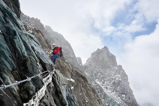 Uomo sorridente che scala una montagna rocciosa in Austria