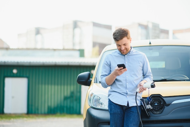 Uomo sorridente che scollega il caricabatterie dall'auto