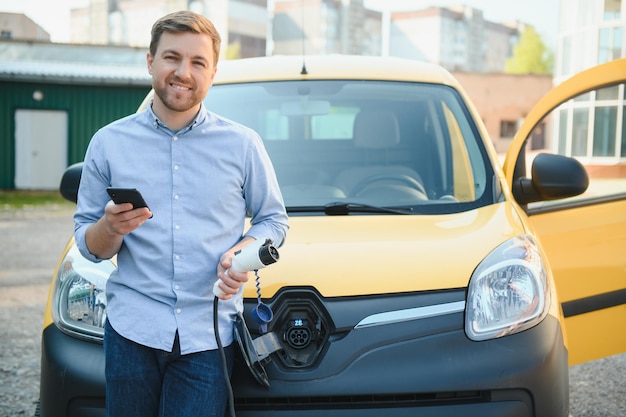 Uomo sorridente che scollega il caricabatterie dall'auto