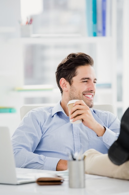 Uomo sorridente che si siede con i piedi sulla tavola