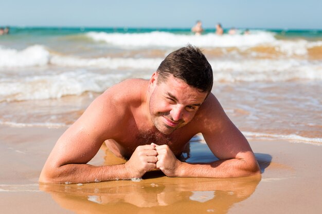 Uomo sorridente che si trova sulla spiaggia su una priorità bassa del mare