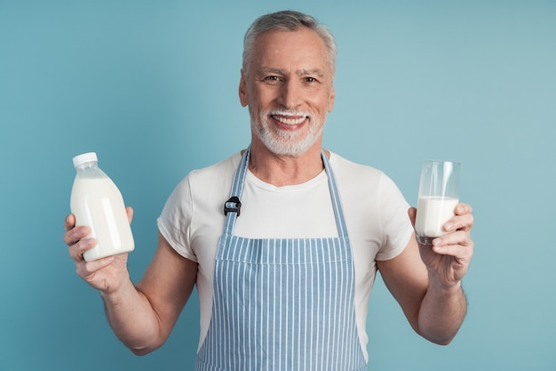 Uomo sorridente che tiene un bicchiere di latte e una bottiglia