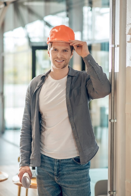 Uomo sorridente che tocca il casco protettivo sulla testa