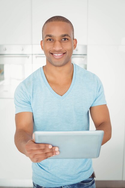 Uomo sorridente che utilizza compressa nella cucina