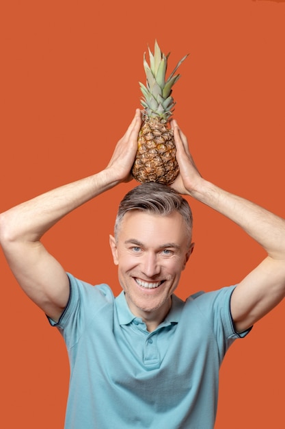 Uomo sorridente con ananas in testa