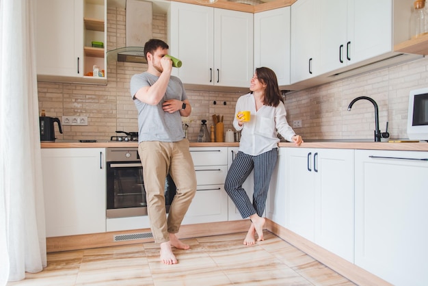 Uomo sorridente con donna in cucina a bere il tè