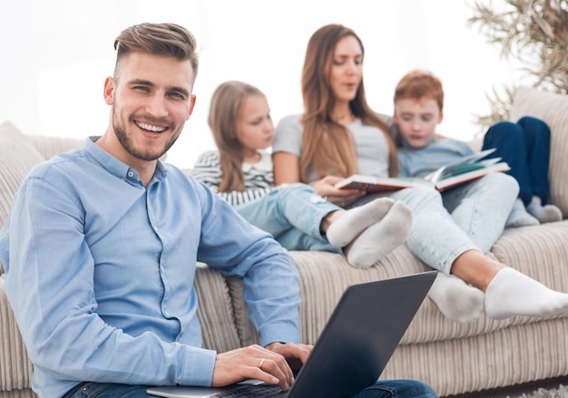 Uomo sorridente con il portatile seduto nel suo soggiorno