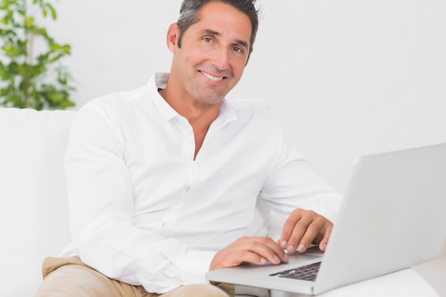Uomo sorridente con il suo laptop