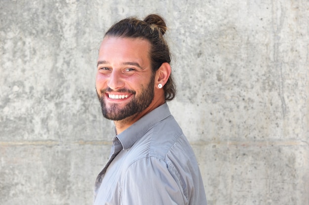 Uomo sorridente con la barba che osserva sopra la spalla