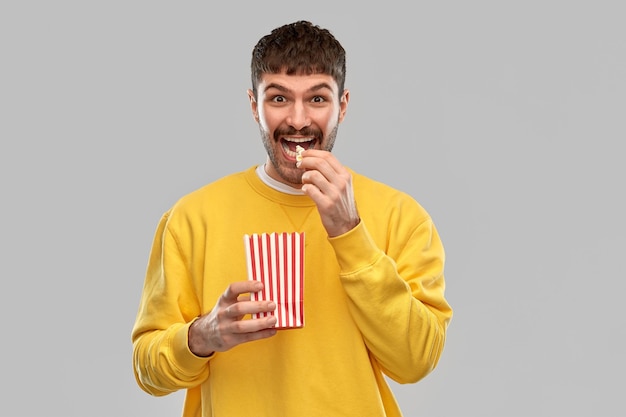 uomo sorridente con la felpa gialla che mangia popcorn