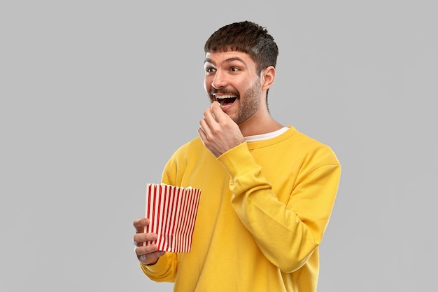 uomo sorridente con la felpa gialla che mangia popcorn