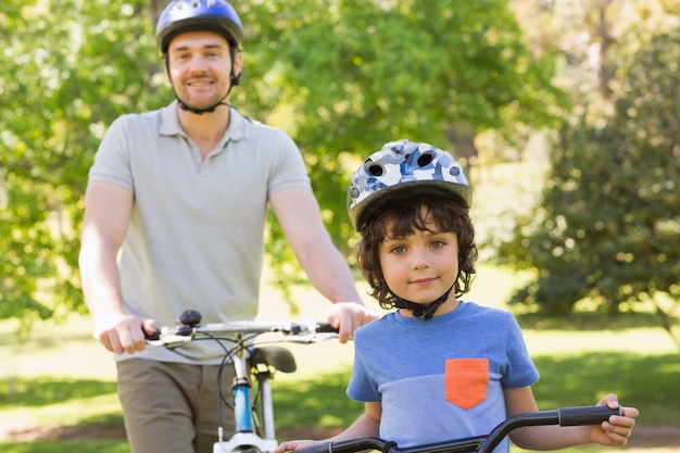 Uomo sorridente con suo figlio in sella a biciclette