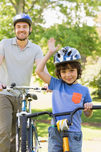 Uomo sorridente con suo figlio in sella a biciclette