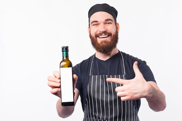 Uomo sorridente del barista che indica alla migliore bottiglia di olio d'oliva