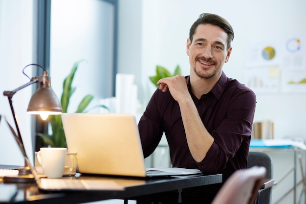 Uomo sorridente del colpo medio al lavoro