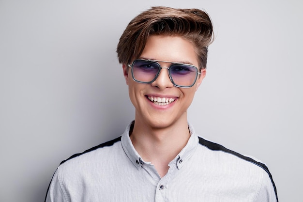 Uomo sorridente di concetto di acconciatura maschile hipster con elegante taglio di capelli in occhiali da sole su sfondo bianco