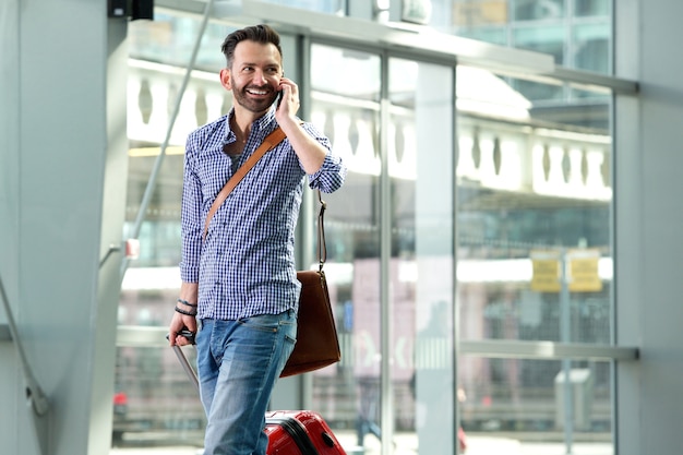 Uomo sorridente di viaggio parlando sul cellulare