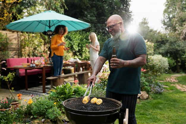 Uomo sorridente di vista laterale che fa barbecue