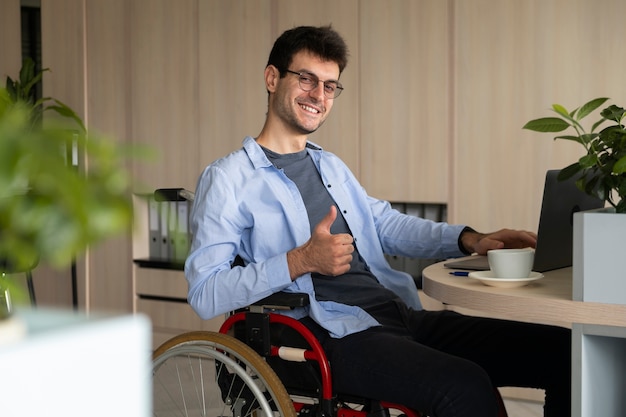 Uomo sorridente di vista laterale in sedia a rotelle al lavoro