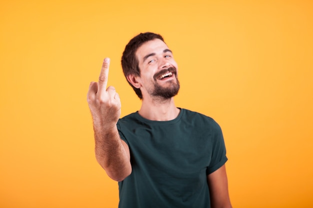 Uomo sorridente felice che mostra il suo dito medio alla macchina fotografica. Gesto osceno