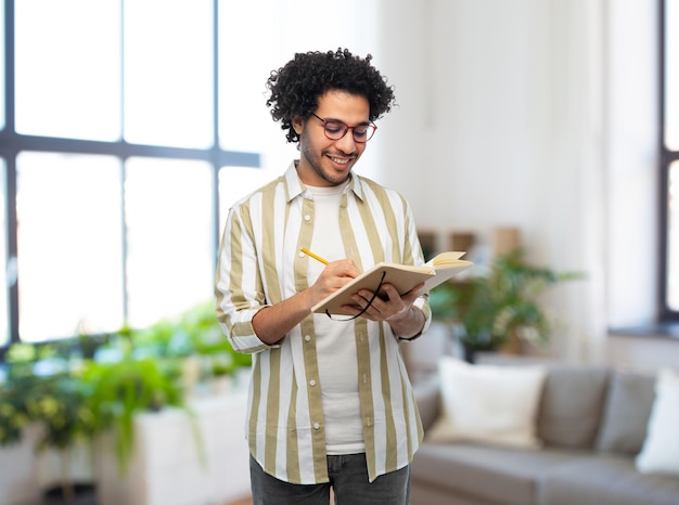 uomo sorridente felice con diario e matita a casa