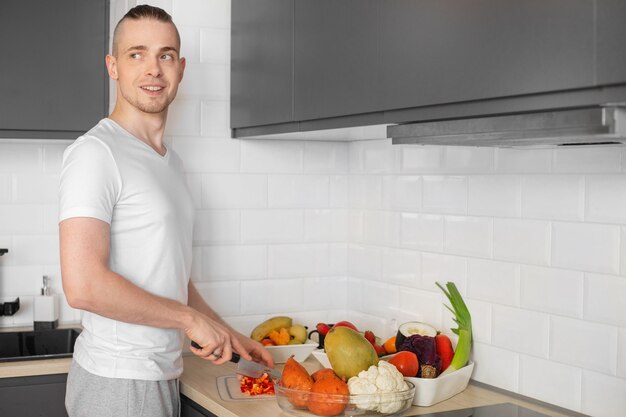 Uomo sorridente in una cucina che taglia le verdure.