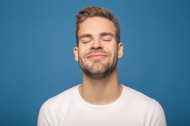 uomo sorridente piacevole con gli occhi chiusi isolato sul blu