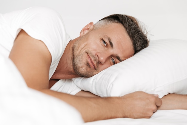 Uomo sorridente sdraiato a letto