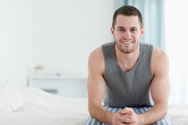 Uomo sorridente seduto sul suo letto