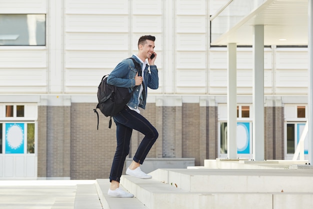 Uomo sorridente sulla telefonata con lo zaino fuori