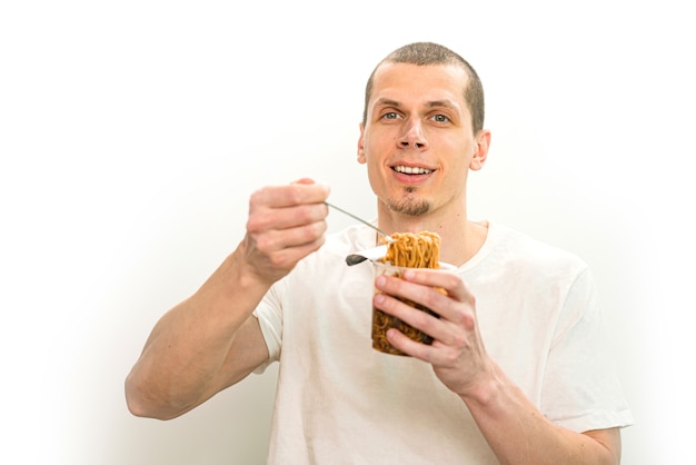 Uomo sorridente tenere una forchetta con spaghetti fast food nel bicchiere di plastica trasparente su uno sfondo bianco.