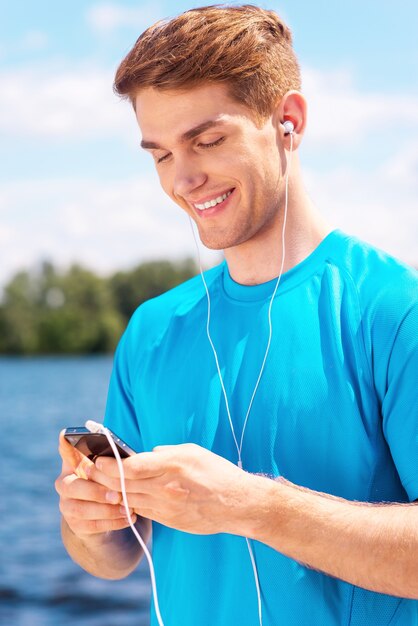 Uomo sportivo. Bel giovane in abbigliamento sportivo in piedi all'aperto e sorridente