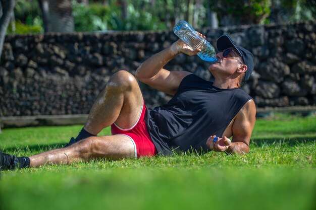 Uomo sportivo che beve acqua nel parco