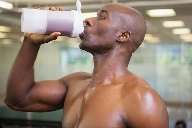 Uomo sportivo che beve proteina in palestra