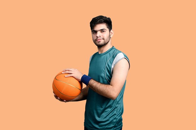 uomo sportivo che tiene pallacanestro e guarda il modello pakistano indiano anteriore