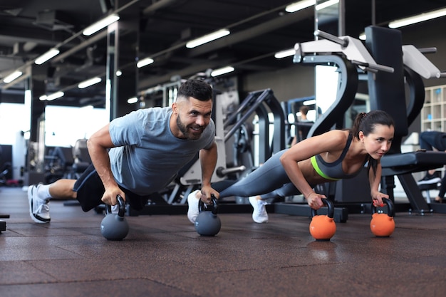 Uomo sportivo e donna che fanno flessioni in palestra.