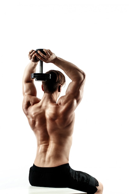 Uomo sportivo in allenamento pompare i muscoli della schiena e le mani con manubri.