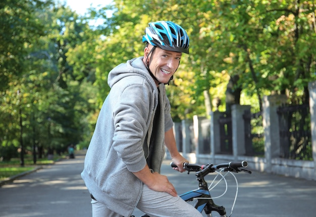 Uomo sportivo maturo con la bicicletta all'aperto