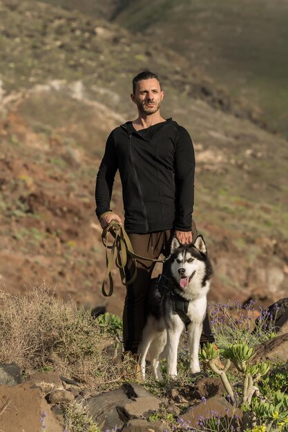 Uomo sportivo sicuro di sé con il cane sulle rocce