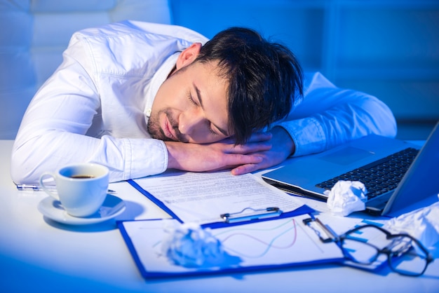 Uomo stanco che dorme sul lavoro con il computer.