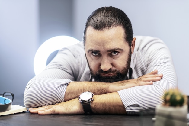 Uomo stanco. Uomo barbuto dai capelli scuri che indossa una camicia a righe che sembra stanco