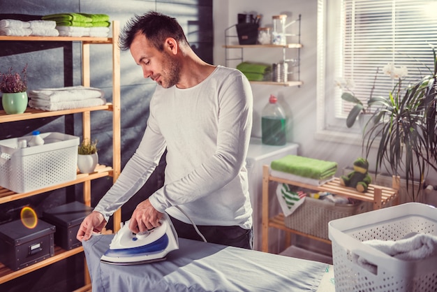 Uomo stiratura vestiti a casa