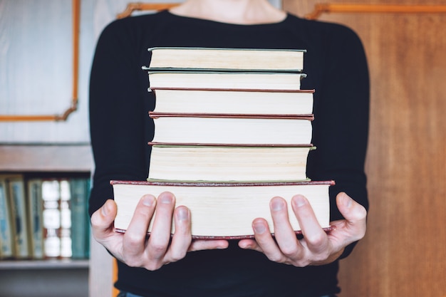 Uomo, studente che tiene molti libri in mano