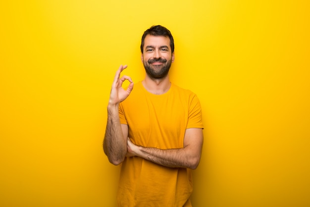 Uomo su colore giallo vibrante isolato che mostra un segno giusto con le dita