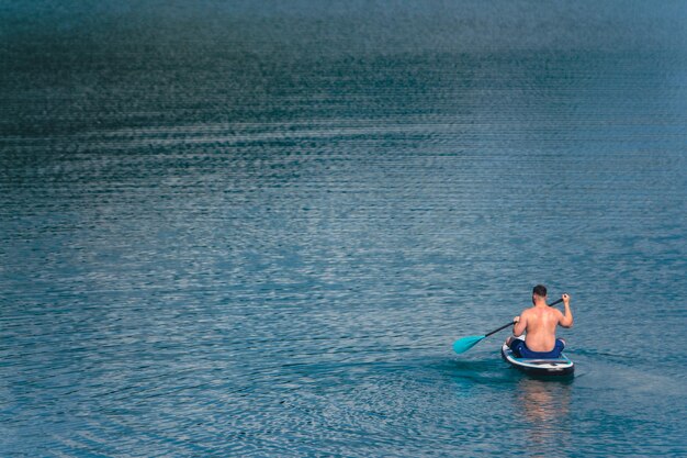 uomo su paddleboard nel mezzo del lago copia spazio